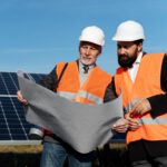 Solar installation professionals reviewing site plans beside solar panels